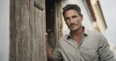 Midcent: En vuxen man står framför en gammal dörr, vilket skapar en känsla av historia och stil. Perfekt för artiklar om mode, inredning eller livsstil. Kategori: Samhälle.