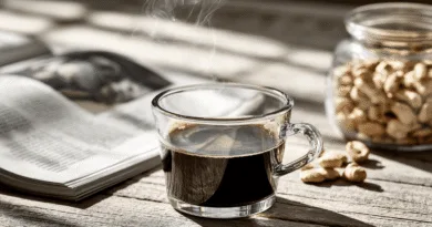 Midcent: En ångande kopp kaffe på ett rustikt träbord med en öppen bok och ett jar av jordnötter i bakgrunden. Perfekt för en avkopplande stund. Kategori: Mat.