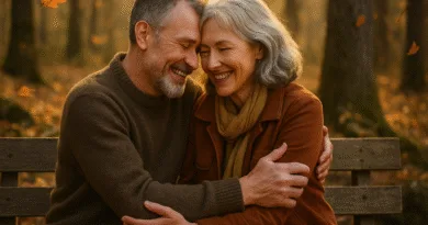 En medelålders man och kvinna omfamnar varandra på en parkbänk under höstens gyllene löv. Stämningen är varm och romantisk. Bild av avkoppling och kärlek i naturen. Perfekt för relationsartiklar.Midcent: Samhälle.