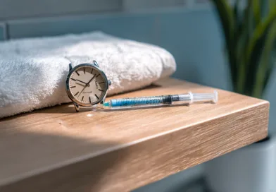Midcent: Klocka och spruta på träyta i badrumsmiljö, symboliserar tid och hälsa. Plats för eftertanke eller daglig rutin.