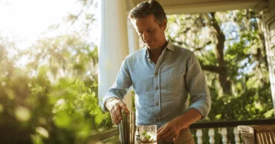 Midcent: En medelålders man står på en veranda och blandar en drink i en cocktailshaker. Solen skiner i bakgrunden och omgivningen är lummig och grönskande. En avkopplande atmosfär genomsyrar bilden. Kategori: Mat.