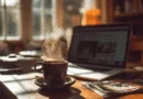 Midcent: En ångande kaffekopp står på ett solbelyst skrivbord, bredvid en bärbar dator och tidningar. Denna scen representerar en avkopplande morgonrutin, idealisk för produktivitet och fokus. Teknik.