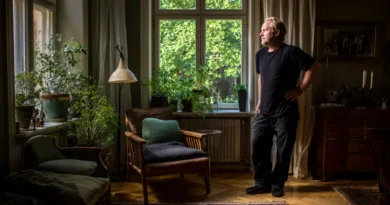 Midcent: En vuxen man står i ett ljust rum omgiven av växter, vilket skapar en lugn atmosfär. Kategorin är Samhälle.