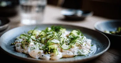 Midcent erbjuder en fräsch och läcker maträtt med skivad fisk, garnerad med krispig gurka och dill. Elegant uppläggning gör det till en visuell njutning, perfekt för finsmakare. Mat.