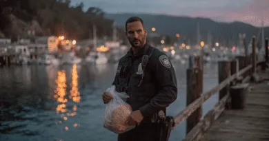 Midcent, en medelålders man i polisuniform, står vid en hamn i skymningen. Han håller en plastpåse, omgiven av glittrande vattenspeglingar och en maritim miljö. Kategori: Samhälle.