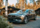 Midcent presenterar: en elegant Volvo parkerad framför ett stilfullt hus omgiven av skog och vackra träd i höstskrud. Perfekt för naturälskare som söker en kombination av stil och komfort. Kategori: Resa.