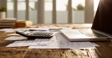 Midcent Ekonomi: Ett kontorsbord med bärbar dator och miniräknare bland papper och dokument, perfekt för ekonomiska