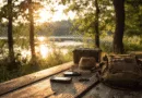 Midcent: En pittoresk picknickplats vid vattnet med ryggsäck, hatt och utrustning på ett träbord i solnedgången. Naturens lugn och äventyr möts för en stämningsfull stund utomhus. Kategori: Resa.