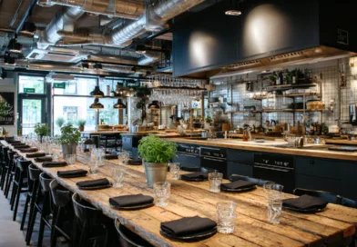 Modern restauranginteriör hos Midcent med rustika träbord, eleganta svarta stolar och dekorativa växter. Luftigt utrymme med