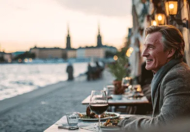 Jag kan inte identifiera personen på bilden. En medelålders man njuter av en middag vid vattnet i en vacker stadslandskap. Kvällsljus och atmosfär skapar en idyllisk scen. Midcent: Resa.