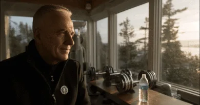 Midcent: En medelålders man sitter meditativt i ett solbelyst hemmagym med utsikt över naturen. Vikter och en vattenflaska syns i bild, vilket understryker en hälsosam livsstil. Kategori: Hälsa.