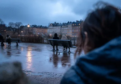 Midcent: En regnig kväll i staden, människor sitter på bänkar vid vattnet. Stämningsfull belysning reflekterar på den våta marken, omgiven av stadens arkitektur. Perfekt för en lugn promenad i skymningen. Kategori: Resa.