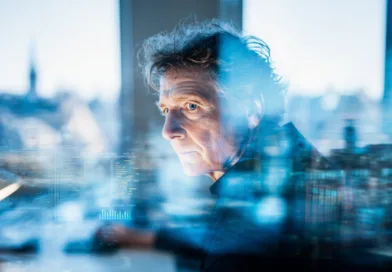 Midcent: En medelålders man arbetar fokuserat vid en dator med teknik och analys i ett modernt kontorslandskap. Bilden förmedlar teknisk innovation och framtidsinriktade lösningar. Kategori: Teknik.