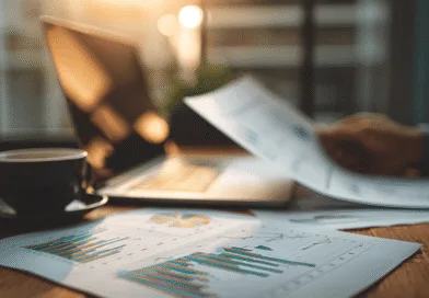 Midcent: En medelålders man analyserar finansiella rapporter vid en laptop med en kopp kaffe bredvid, i mjukt solljus. Professionell analys och ekonomisk planering i fokus.Kategori: Ekonomi.