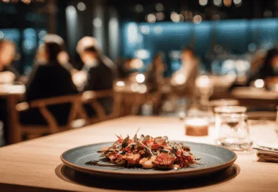 Midcent: Ett elegant serverat gourmetmåltid står i fokus i en stämningsfull restaurangmiljö med dämpad belysning och människor i bakgrunden. En perfekt kombination av smak och stil för en lyxig matupplevelse. Kategori: Mat.
