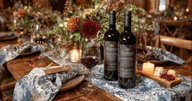 Midcent: En elegant middagsdukning med två flaskor rött vin, vin glas och smakfulla blomsterdekorationer. En atmosfär av värme och stil med levande ljus som förhöjer upplevelsen. Perfekt för vinälskare och gourmeter. Kategori: Mat.