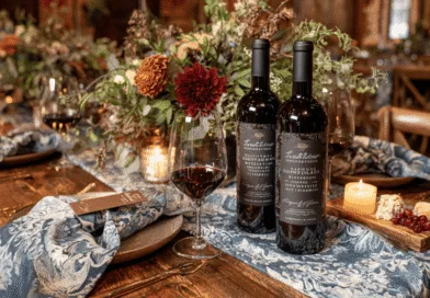 Midcent: En elegant middagsdukning med två flaskor rött vin, vin glas och smakfulla blomsterdekorationer. En atmosfär av värme och stil med levande ljus som förhöjer upplevelsen. Perfekt för vinälskare och gourmeter. Kategori: Mat.