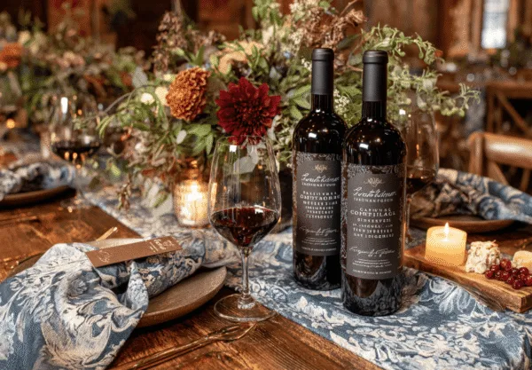 Midcent: En elegant middagsdukning med två flaskor rött vin, vin glas och smakfulla blomsterdekorationer. En atmosfär av värme och stil med levande ljus som förhöjer upplevelsen. Perfekt för vinälskare och gourmeter. Kategori: Mat.