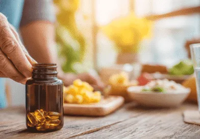 Midcent: En medelålders man vid ett bord sträcker sig efter en flaska med kapslar, omgiven av hälsosam mat och ett glas vatten i solljus. Fokus på kosttillskott och välbefinnande. Kategori: Hälsa.